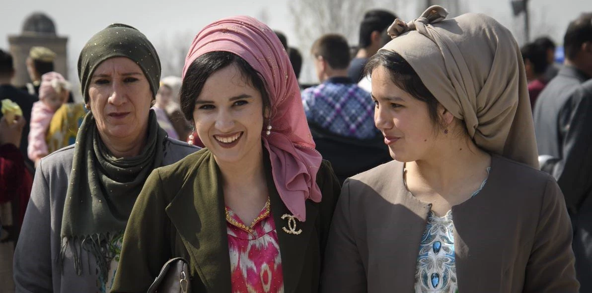 Three women wearing headscarves and smiling next to each other.