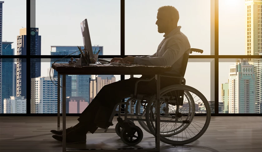 image: Disabled Businessman Sitting In Wheelchair Using Computer At Workplace