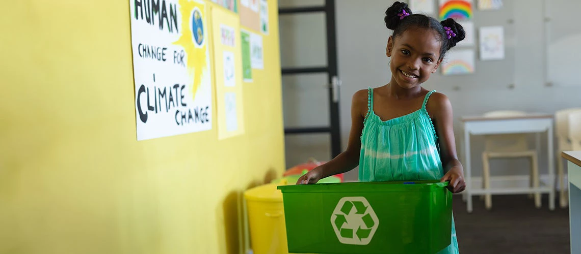 Elementary schoolgirl holding recycle container in school. | © shutterstock.com