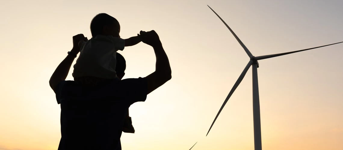 A father and son playing at the wind turbines generating electricity. Credit: Arkom Suvarnasiri/Shutterstock.com