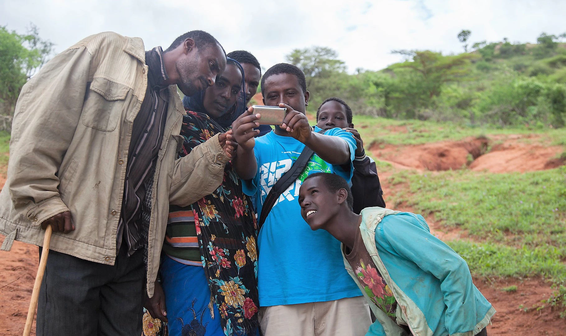 A pastoralist family looks at their picture on a smartphone in Borana, Ethiopia. Photo: ILRI/Flickr