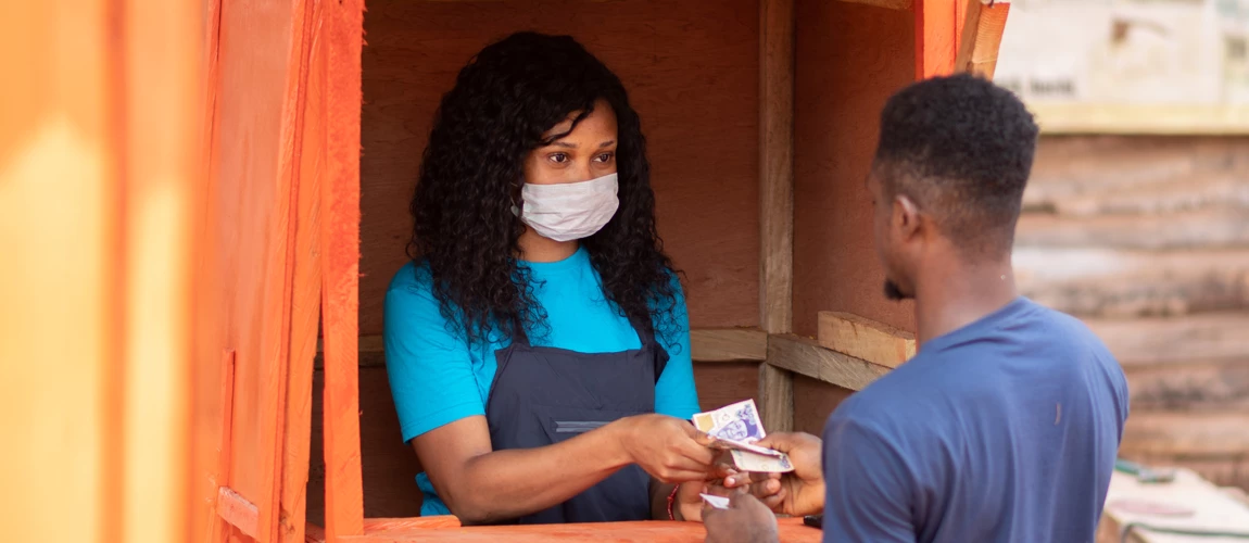 Una mujer nigeriana en un quiosco de servicios entrega dinero a un cliente