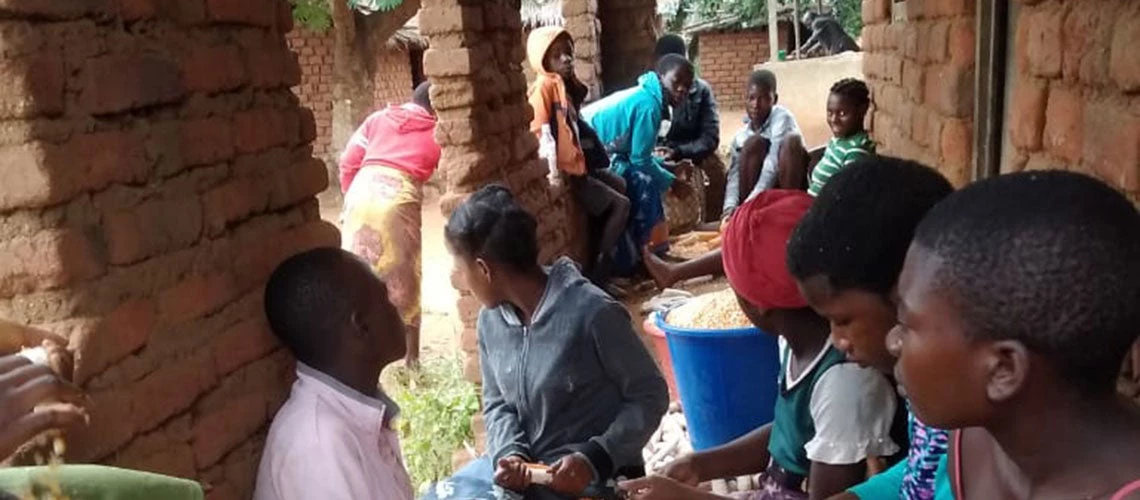 Young people manually shelling the highly nutritious orange maize