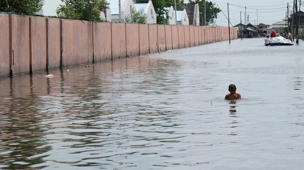 Boy walking in flooded street, Jakarta