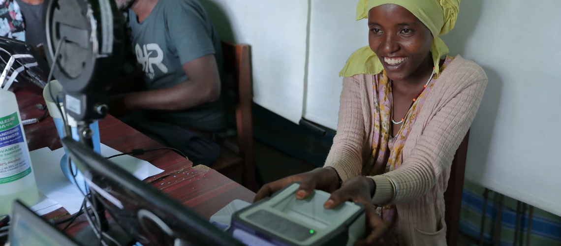 An African woman smiles broadly while getting her biometrics done at the national identity office