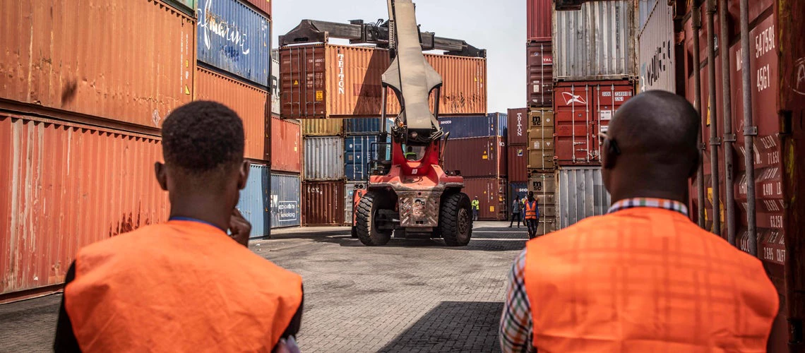 Two port staff supervise the unloading of containers at the Port of Banjul, managed by the GPA - Gambia Port Authority. 