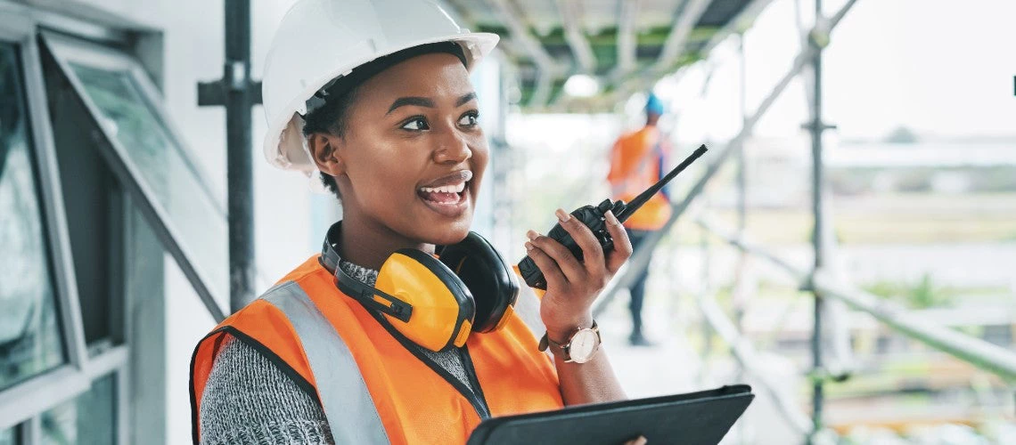 A black female engineer holds a tablet and walkie talkie while checking the progress of an infrastructure project in Haiti