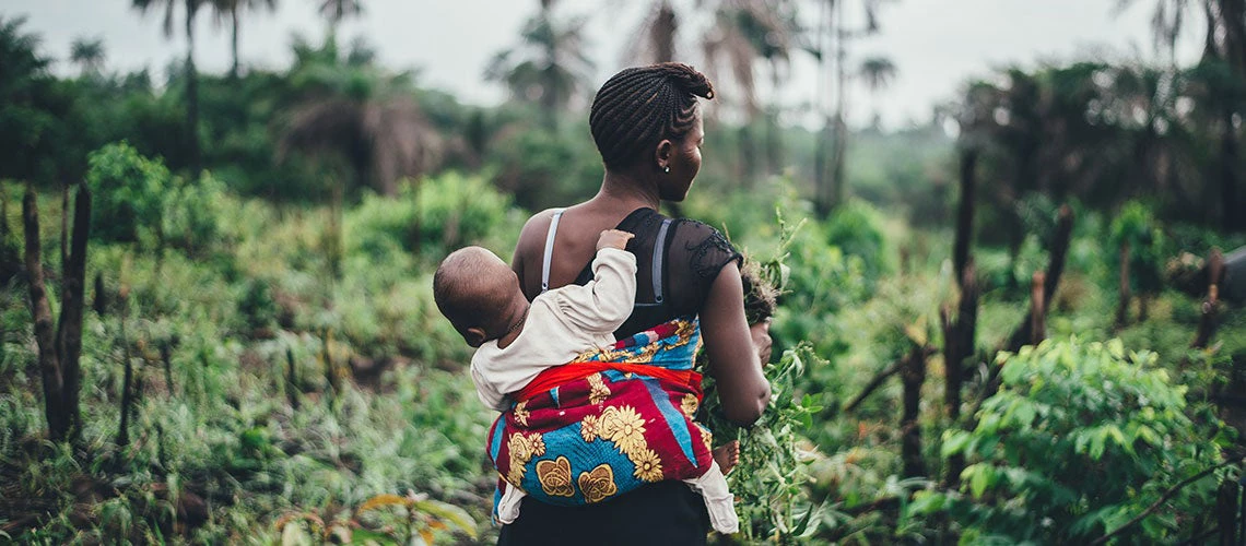 Indigenous female farmer combining childcare and farming activities.