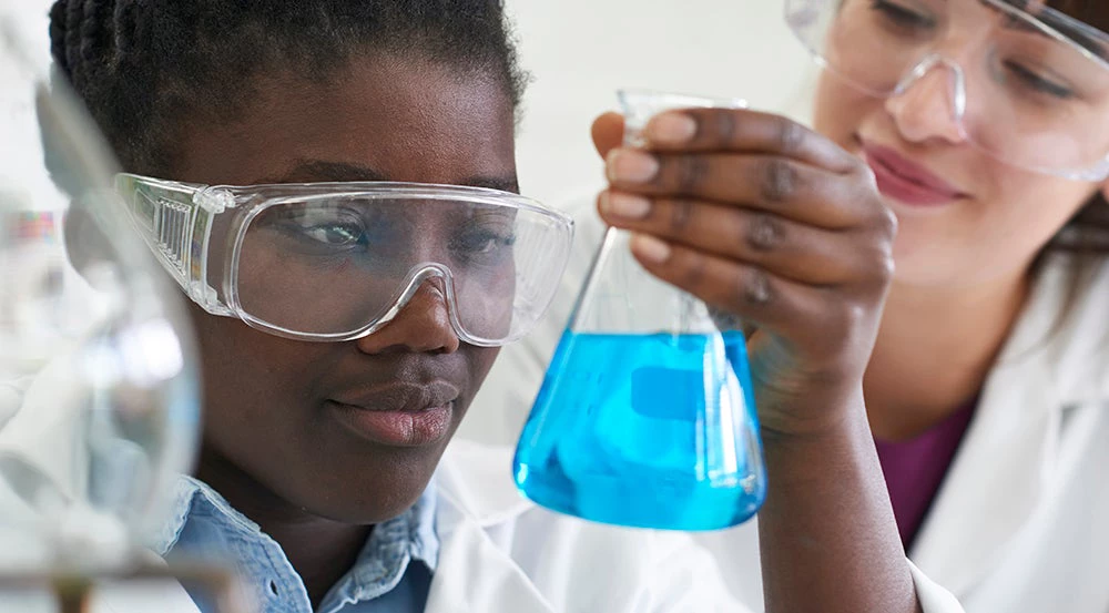 Female Pupil And Teacher Conducting Chemistry Experiment / iStock/MachineHeadz