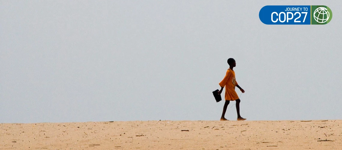 Girl walking to school in an arid landscape in Ghana