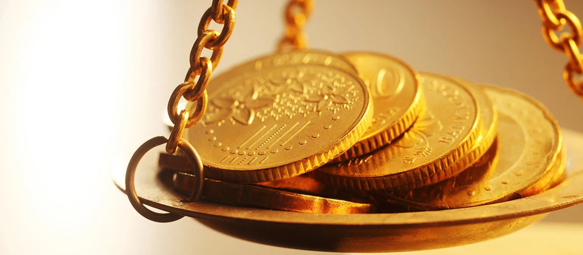 Stack of shiny gold coins placed on weighing scale | © shutterstock.com