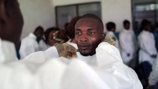 A health worker wearing personal protective equipment helps another health worker with his protective gear during a training session on Ebola in Sierra Leone. At least 100 health staff have died this year from Ebola in Sierra Leone alone. © John James/UNICEF