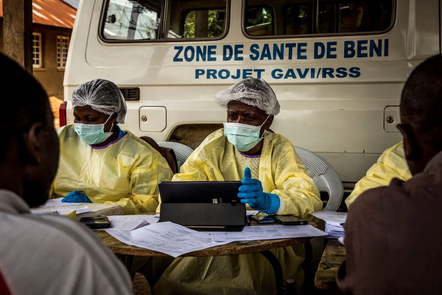 Two health care workers use a computer to record information from a patient in Beni, Democratic Republic of Congo