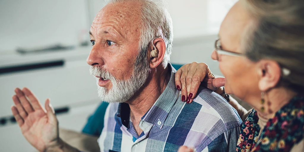 A man tries a hearing aid and looks surprised. 