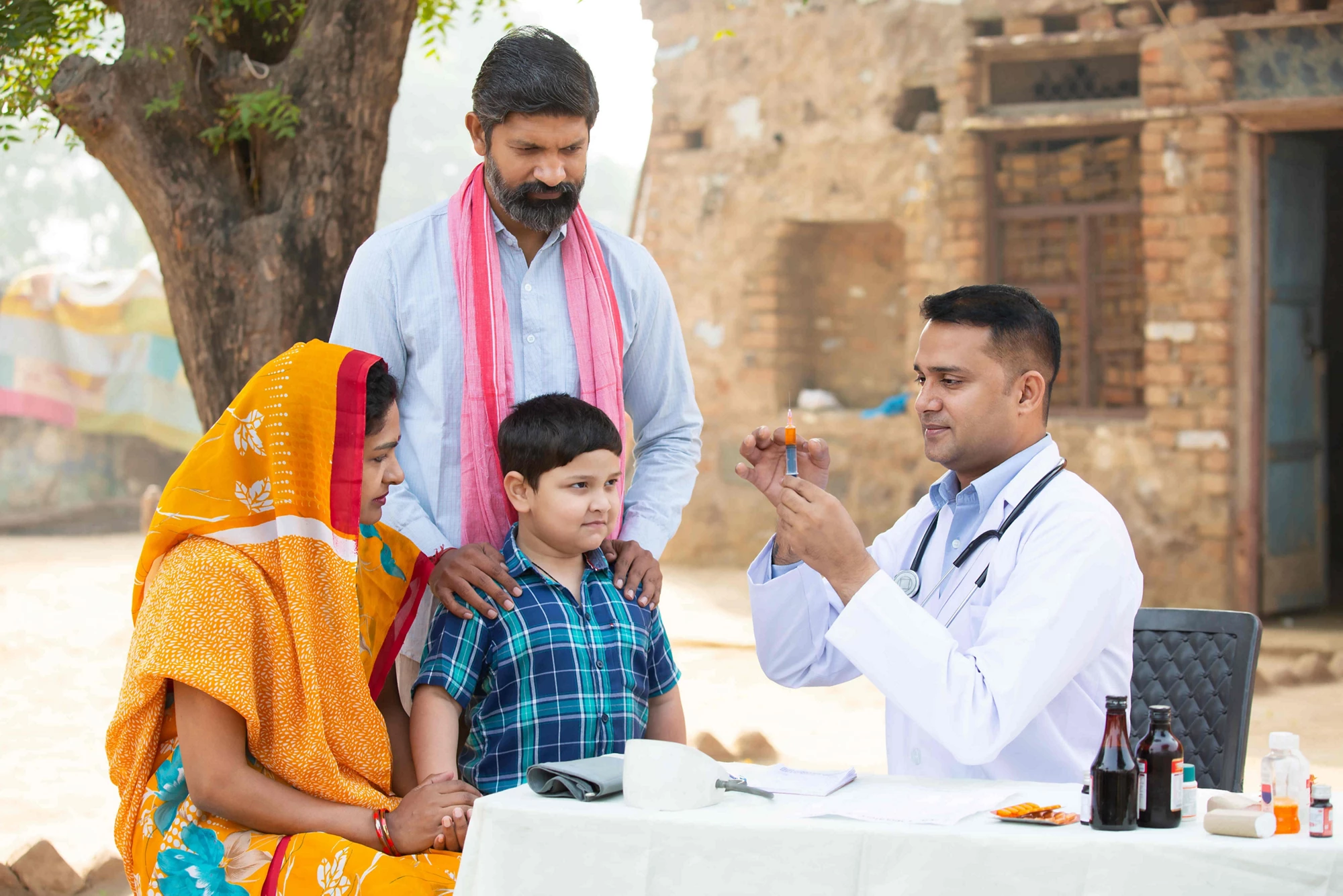 Doctor with a little boy and his mother and father at a village healthcare center in rural India. 