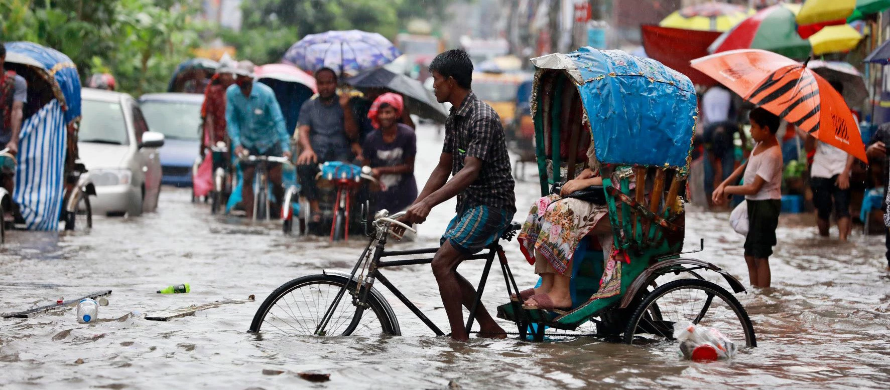 Picture of man cycling through flooded street in Bangladesh