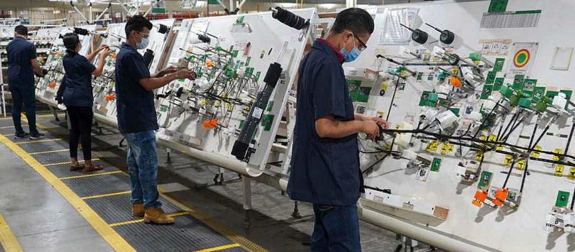 Workers wearing face masks operate standing appliances in a factory