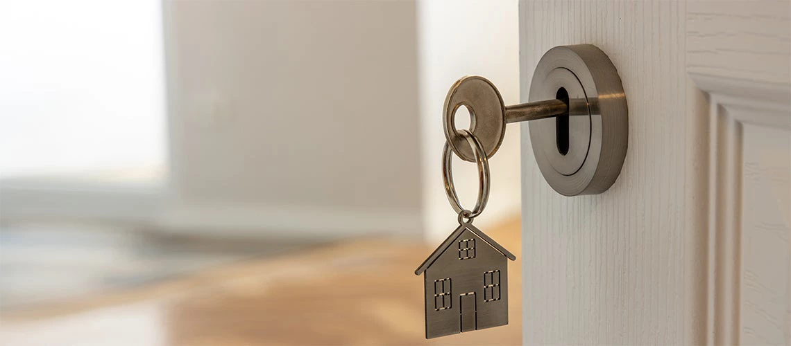 Open door to a new home with key and home shaped keychain | © shutterstock.com