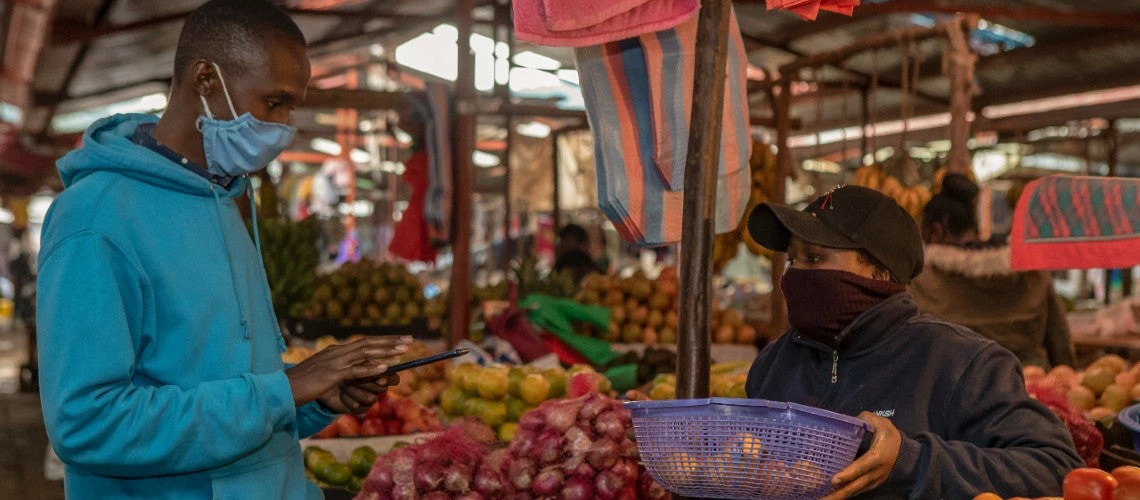 A Kenyan man uses his photo to make a payment at a fruit stall in a Nairobi market