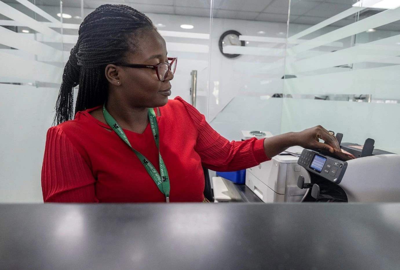 A teller at the Bank of Africa counts money at a bank window at the main branch downtown.