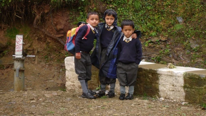 Children wait for the car pool to take them to school in town.