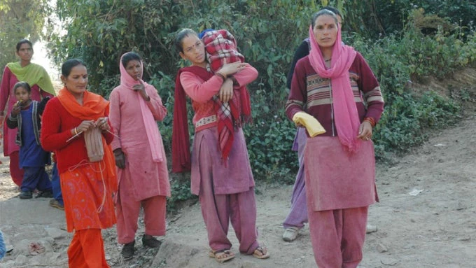 Women walk up from their homes to the road