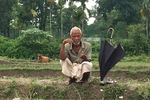 A paddy farmer with his umbrella on a rainy day in West Bengal, India. Photo by Amit Jain / World Bank