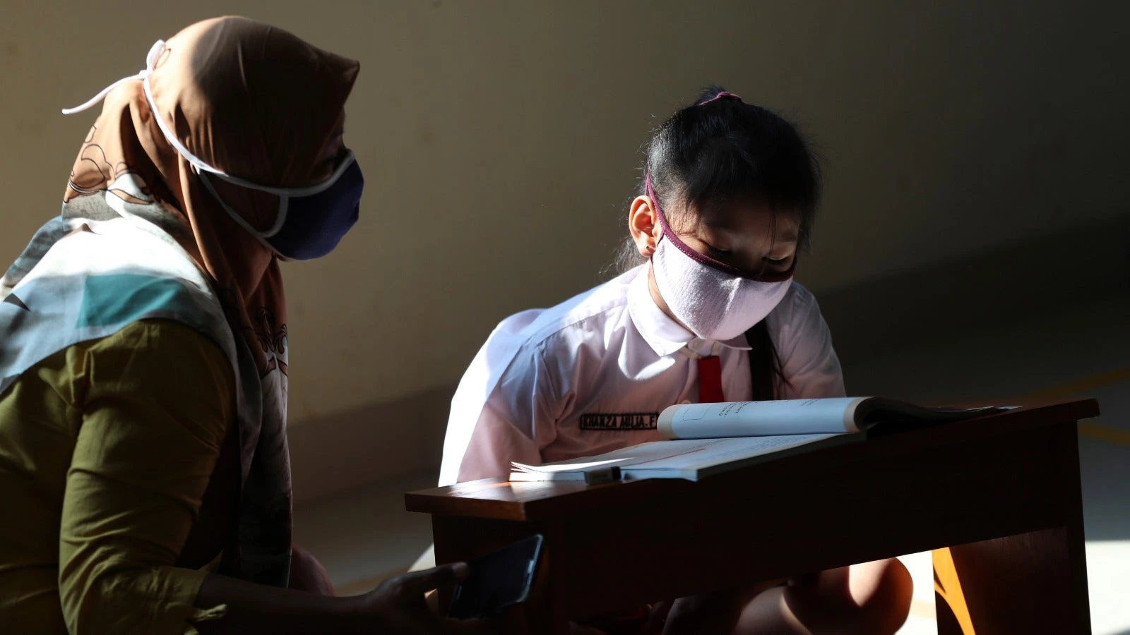 A mother looks on while her daughter uses the free Wi-Fi in the village office to study.  