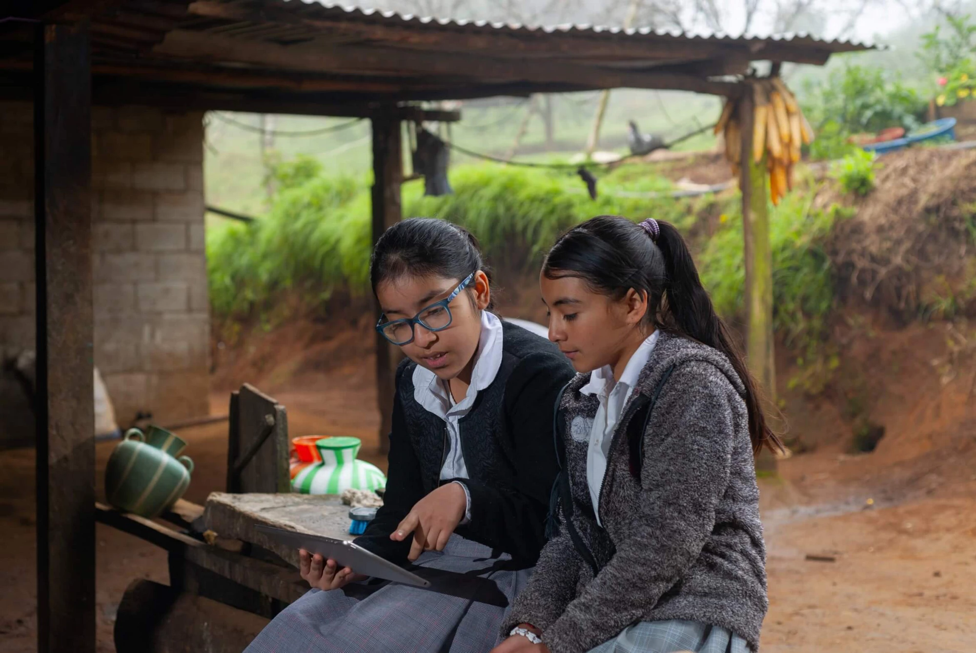 Two young girls in a village in Peru use a tablet to complete their after school activities