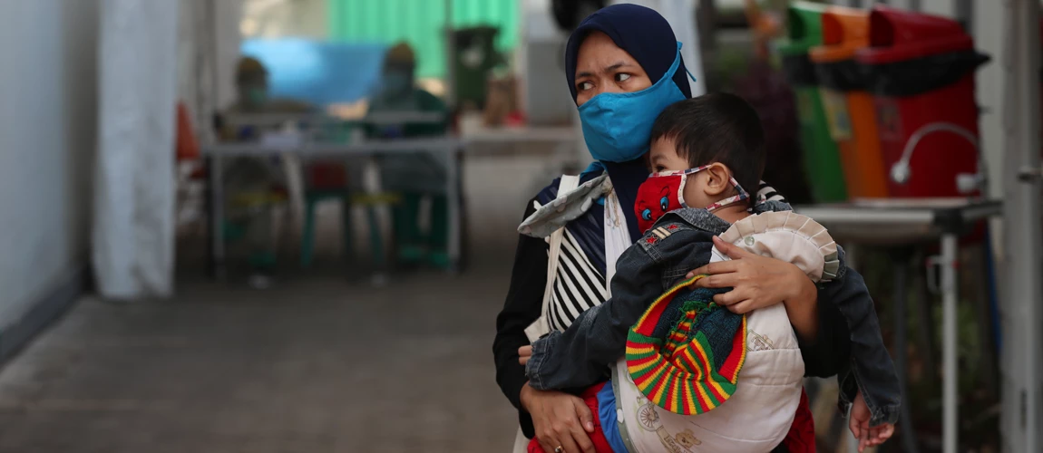 A women carries her child at a community health center amid coronavirus outbreak in Jakarta, Indonesia