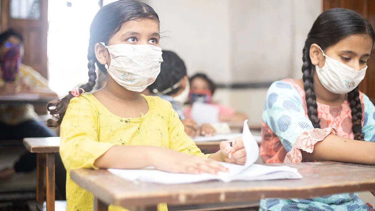 Girls return to school and pay attention to their teacher, wearing their masks.