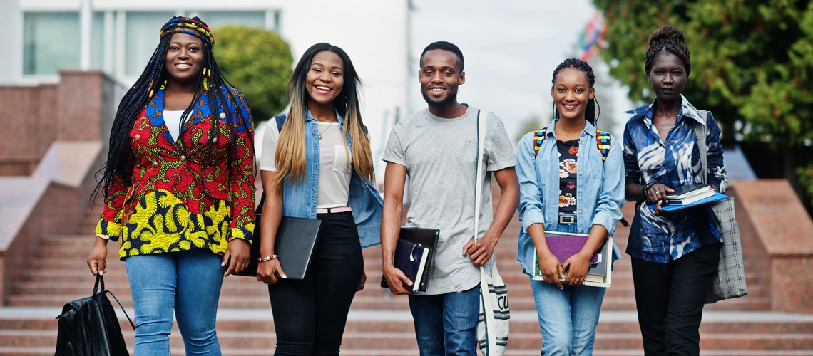 Group of five african college students spending time together on campus at university yard. 
