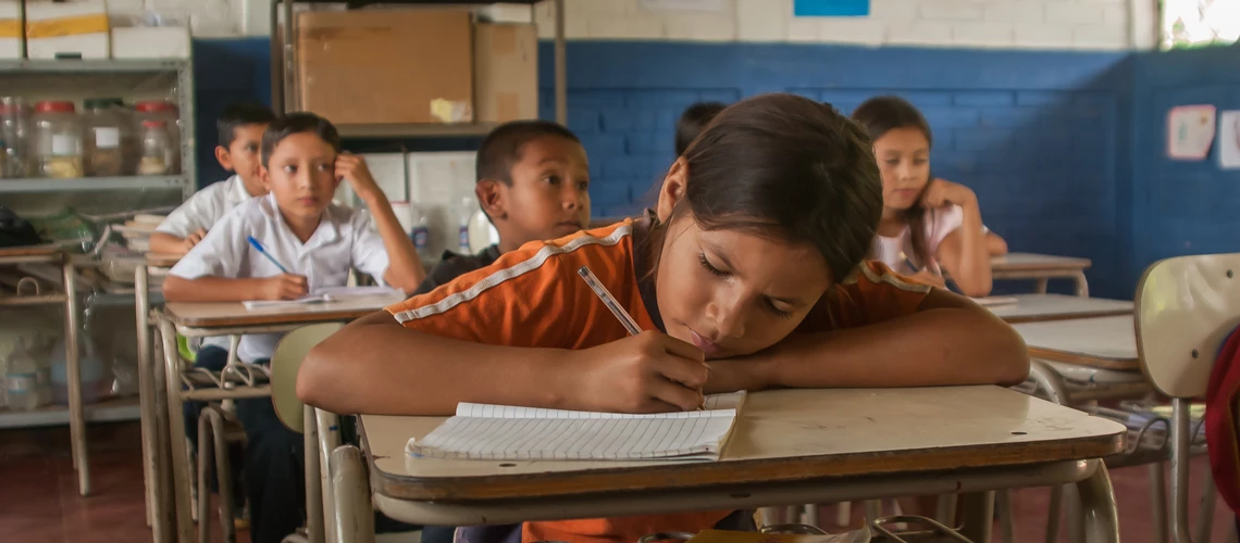 Suchitoto, El Salvador. 03-18-2019. Portrait of a girl at school writing in the classroom in the old town of Suchitoto. Gonzalo Bell / Shutterstock.com