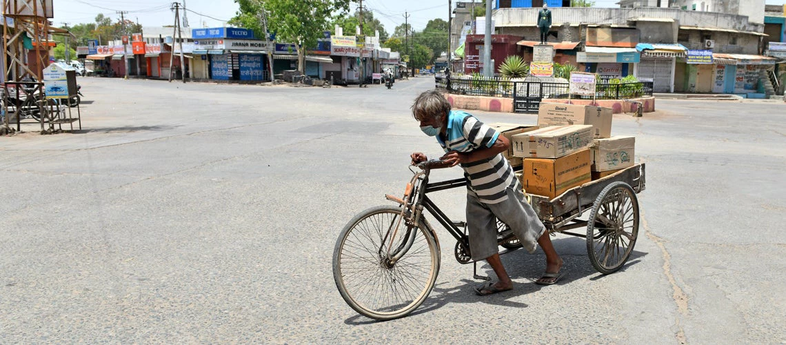 Indian labourer pushes a tri-cycle cart laden with consumer goods at a deserted market during ongoing COVID-19 lockdown in Beawar.