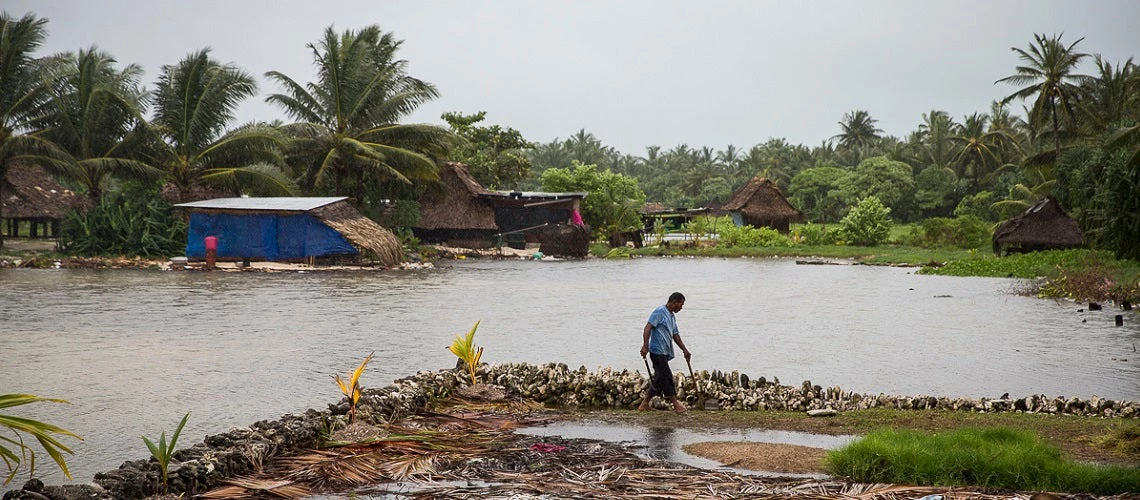 A man walks along an area partially flooded inside a sea wall in Bonriki, an area close to the airport on South Tarawa, Kiribati.