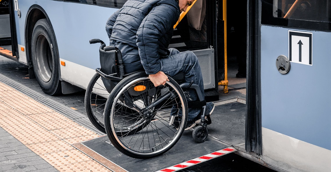 Person with a physical disability enters public transport with an accessible ramp.