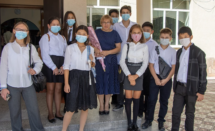 students in school uniforms stand together in front of a school