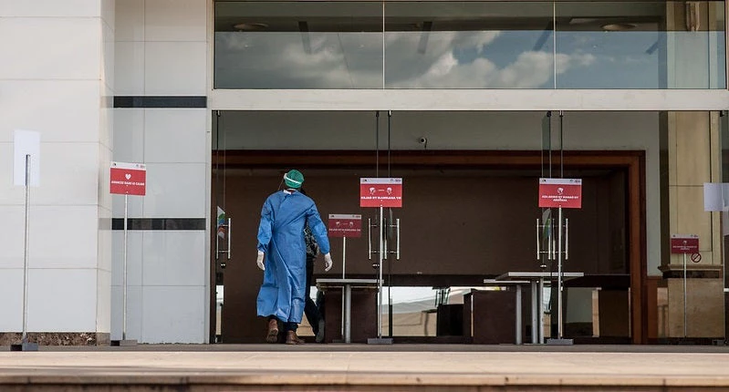 Person walks into a COVID testing center in Madagascar, wearing PPE