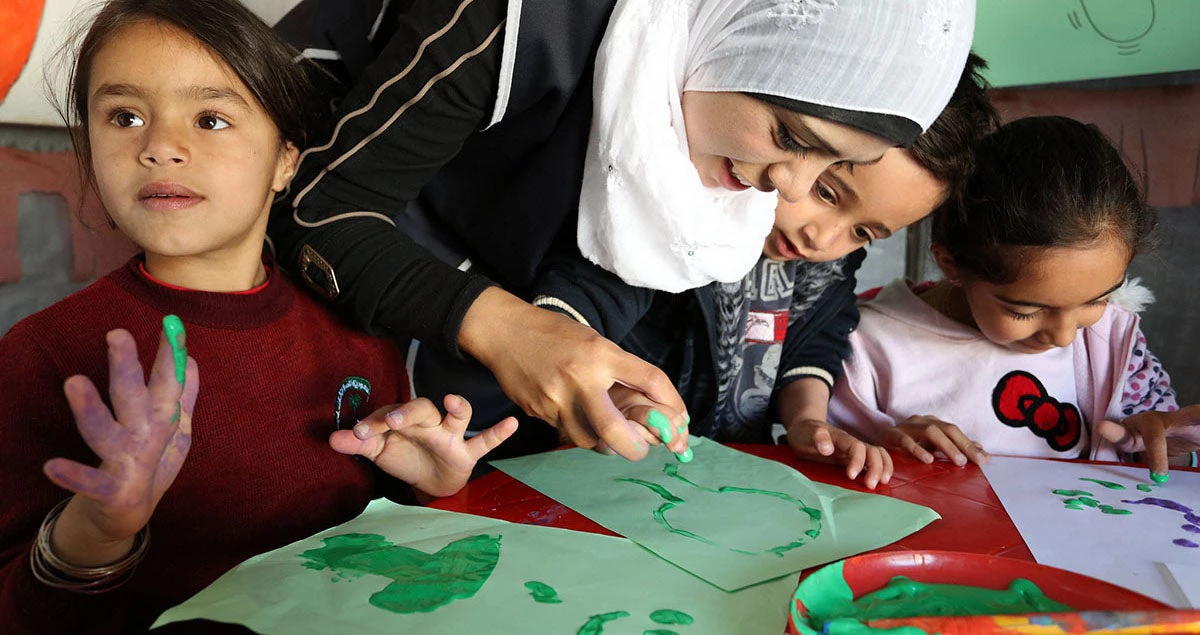Niños refugiados sirios aprenden a pintar con los dedos.