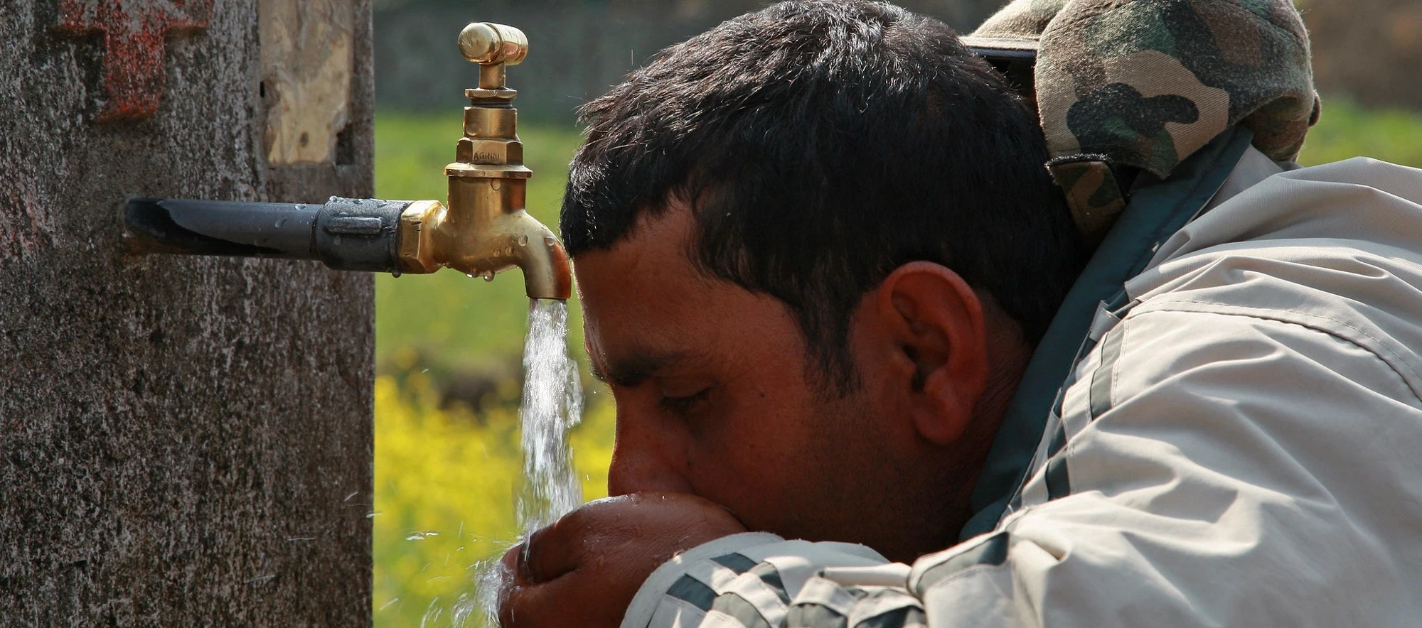 Man drinking from water tap. Photo by Simone D. McCourtie