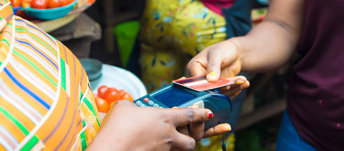 A woman paying bills online using a bank card in a local market. Photo credit: Shutterstock