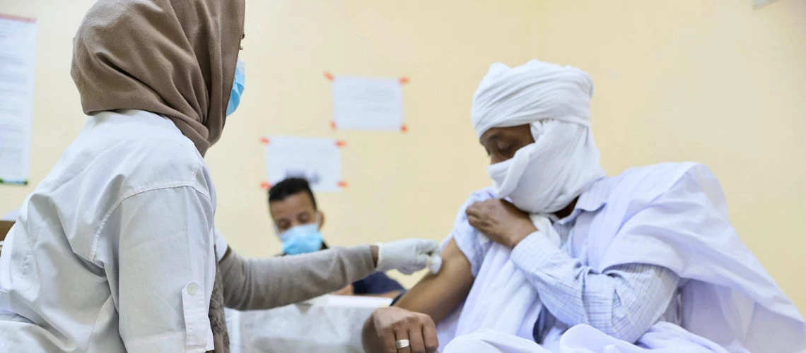 A female health care worker vaccines a man against Covid-19 at the Maughataa Medical Center in Teyarett, Mauritania. Photo credit: World Bank