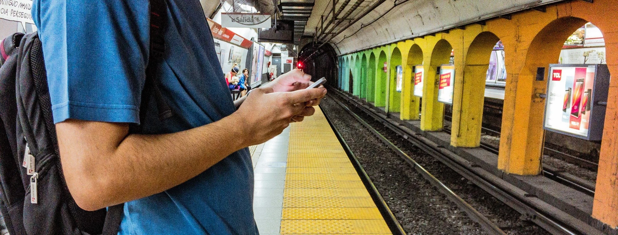 Hombre manipulando un teléfono celular en una estación de tren en la Ciudad de Buenos Aires. 
