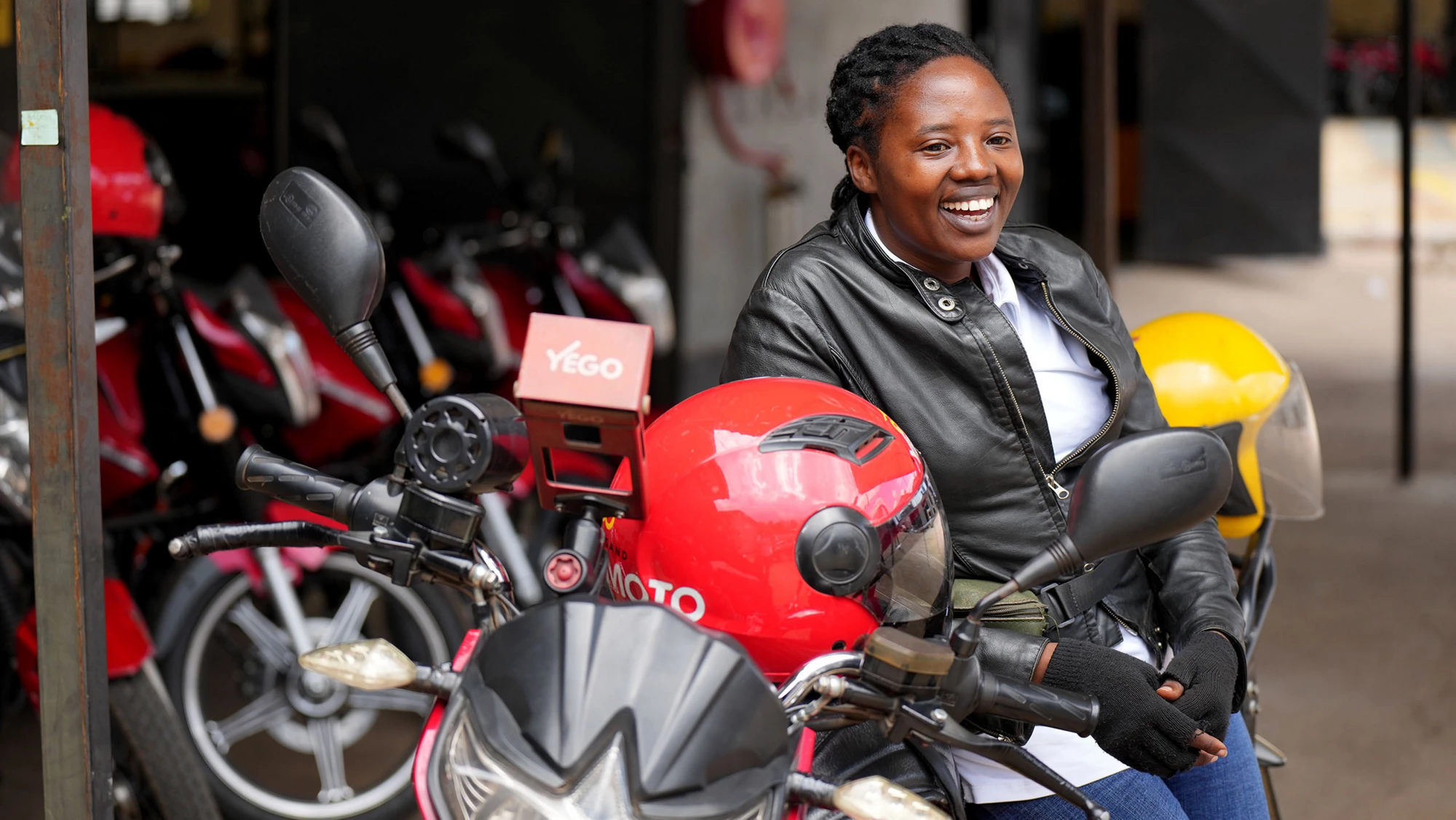 Vêtue d’une veste en cuir noir, d’un jean et de baskets blanches, avec un casque rouge pétant, Numukobwa Dative conduit une moto électrique à Kigali, au Rwanda. Photo par Julia Schmalz/IFC