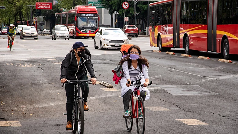 MEXICO CITY, MEXICO - SEPTEMBER 13, 2020: A couple of women riding bikes in the avenue next to the metrobus.