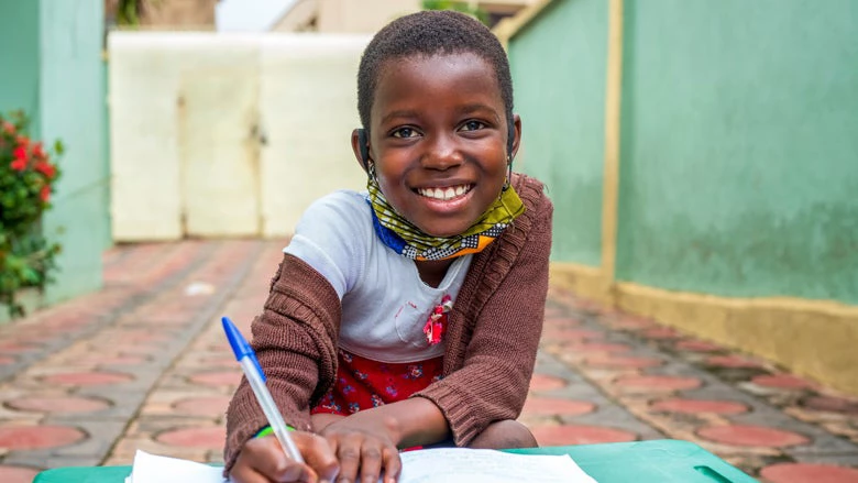 Portrait d'un jeune enfant faisant ses devoirs et souriant à la caméra. Yaw Niel/Shutterstock