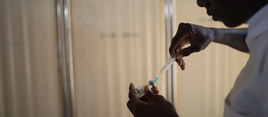 A Nigerian man is seen withdrawing a vaccine?s diluent from a vial and transferring it into a syringe