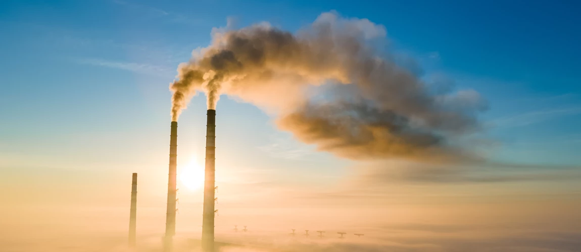 Aerial view of coal power plant high pipes with black smoke moving up polluting atmosphere at sunset.