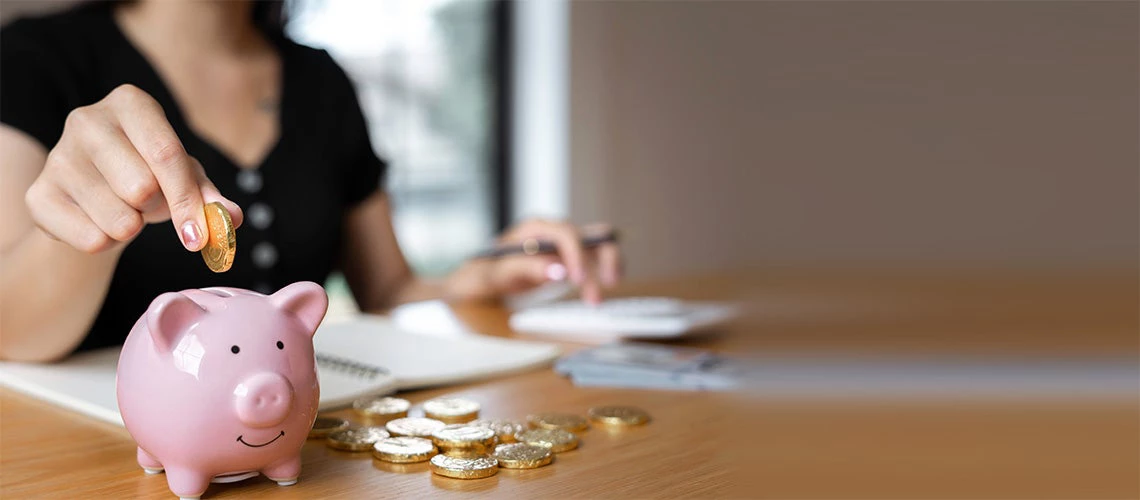 Adding coins into a piggy bank | © shutterstock.com