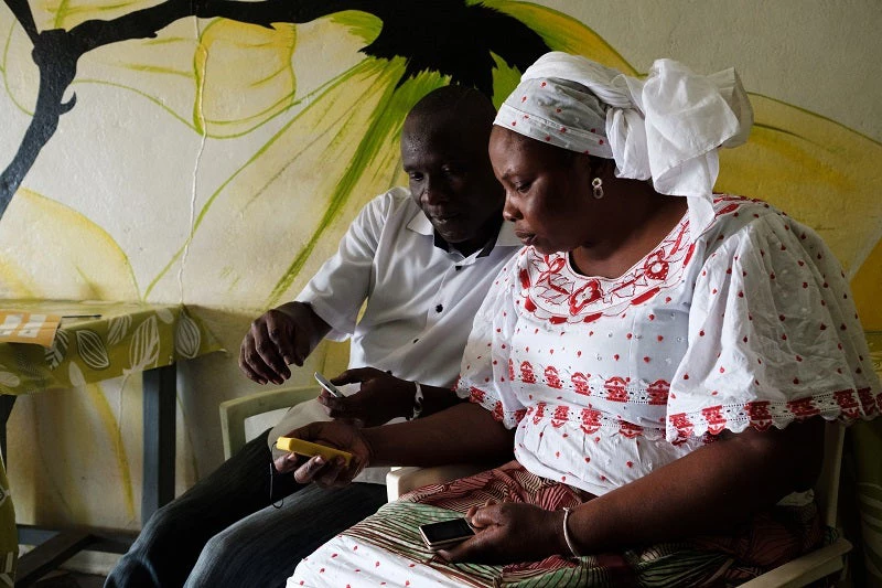 Rokiatou Doumbia, owner of Café Vert in Abidjan, Côte d'Ivoire, with Steve Bedan, MoMo Tap Sales Team Supervisor, as she learns to use a MoMo Tap point-of-sale device.